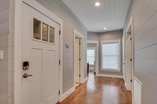 corridor with visible vents, wood walls, baseboards, recessed lighting, and light wood-style flooring