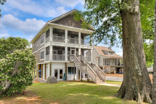rear view of property featuring stairs, ceiling fan, a sunroom, french doors, and a yard