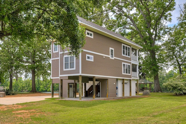 rear view of property with stairs, a yard, and driveway