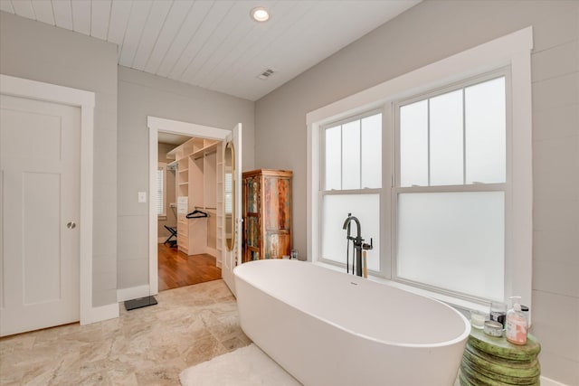 full bathroom with recessed lighting, visible vents, a soaking tub, and a spacious closet