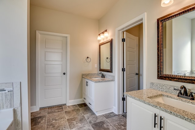 full bathroom featuring two vanities, a sink, and baseboards