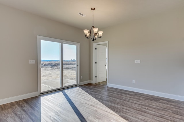 empty room with visible vents, baseboards, dark wood finished floors, and a notable chandelier