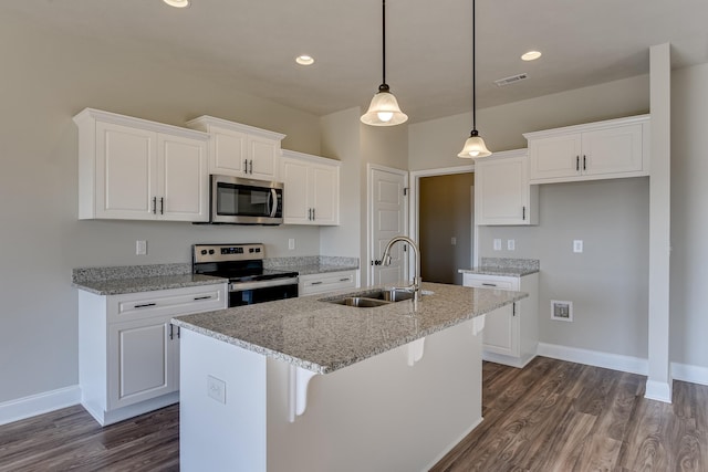 kitchen featuring stainless steel appliances, visible vents, white cabinetry, a sink, and an island with sink