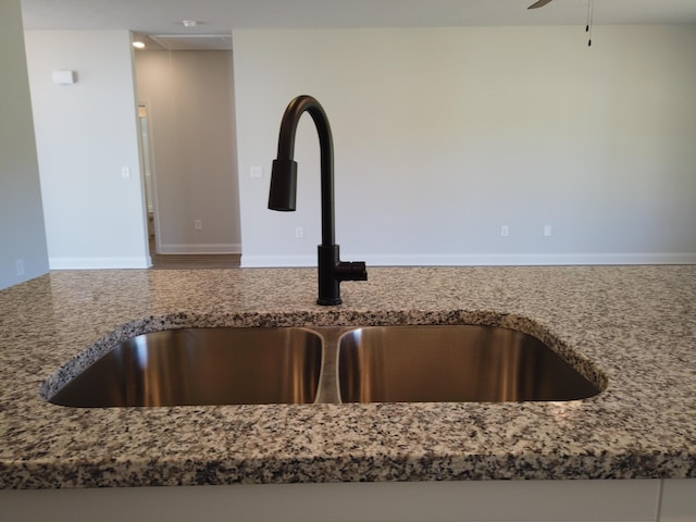 interior details featuring stone countertops, a sink, a ceiling fan, and baseboards