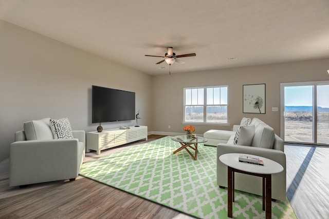 living area featuring ceiling fan, baseboards, and wood finished floors