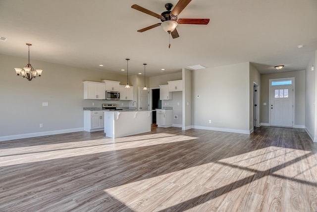 unfurnished living room featuring light wood finished floors, recessed lighting, visible vents, baseboards, and ceiling fan with notable chandelier