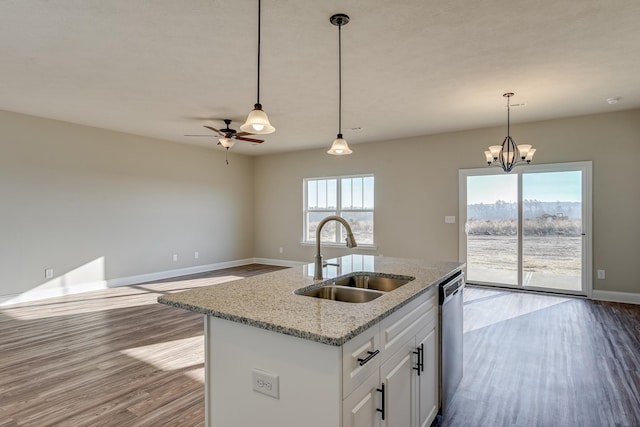 kitchen with wood finished floors, hanging light fixtures, stainless steel dishwasher, and a sink