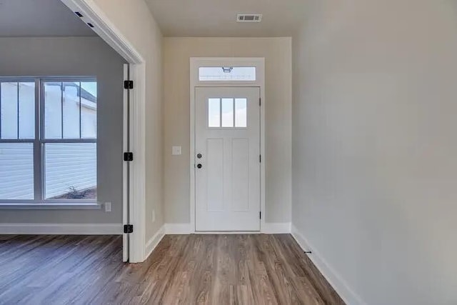 doorway to outside featuring a wealth of natural light, baseboards, visible vents, and wood finished floors