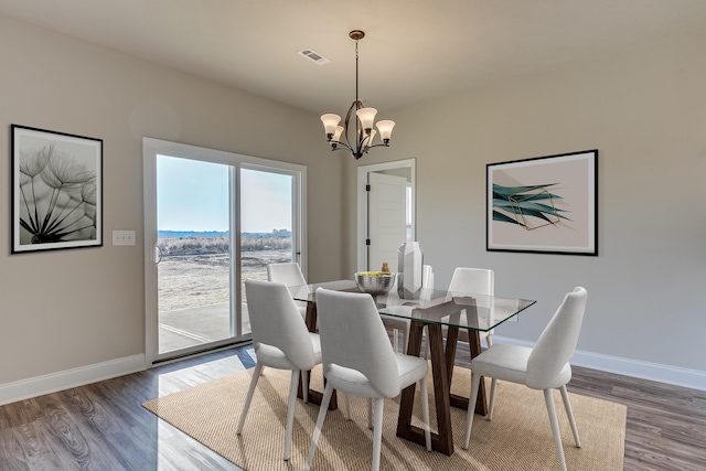 dining area featuring wood finished floors, visible vents, baseboards, and an inviting chandelier