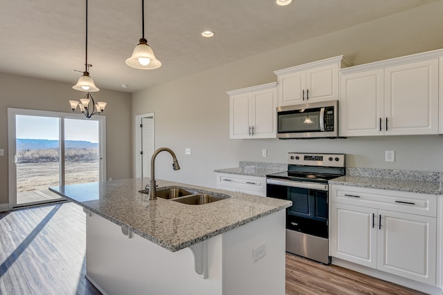 kitchen featuring a sink, white cabinetry, light wood-style floors, appliances with stainless steel finishes, and a center island with sink