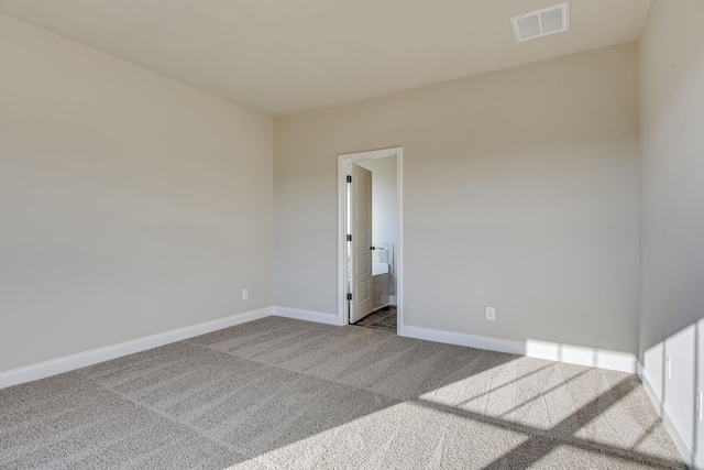 spare room featuring carpet, visible vents, and baseboards