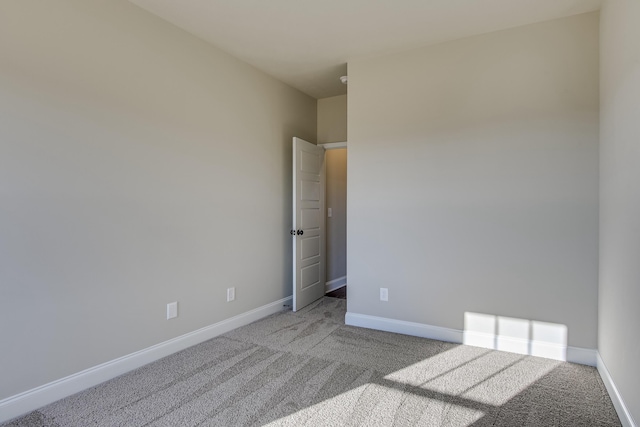 carpeted empty room featuring baseboards