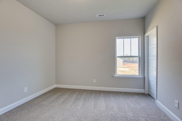 carpeted spare room with visible vents and baseboards