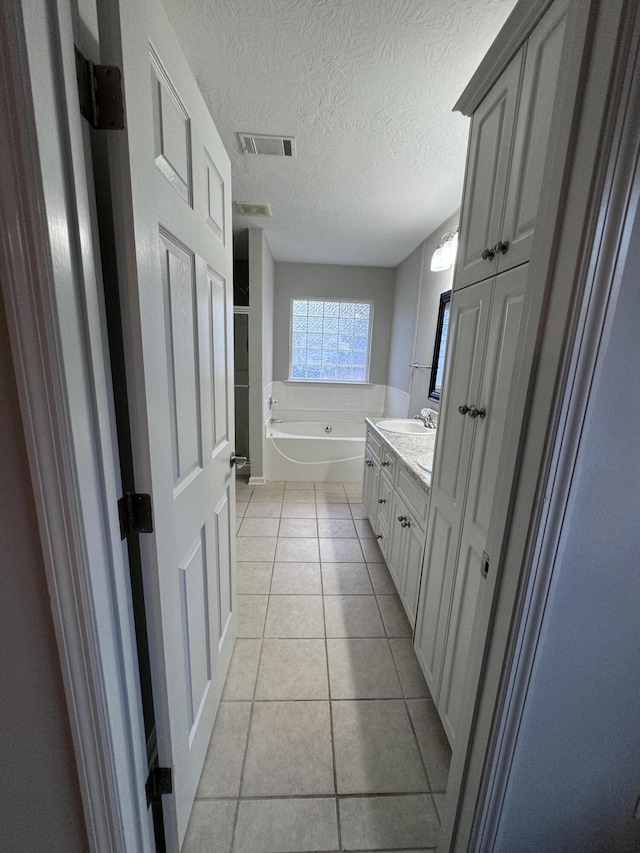 bathroom with tile patterned floors, a bathtub, a textured ceiling, and vanity