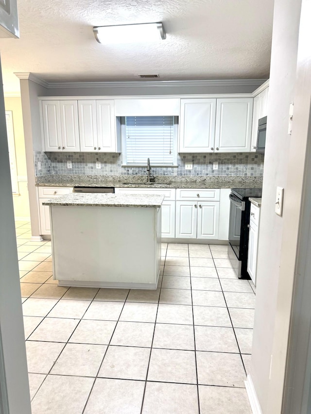 kitchen with electric range, white cabinets, light tile patterned flooring, and a kitchen island