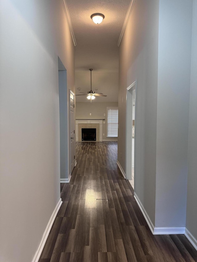 hallway with a textured ceiling, dark hardwood / wood-style floors, and crown molding