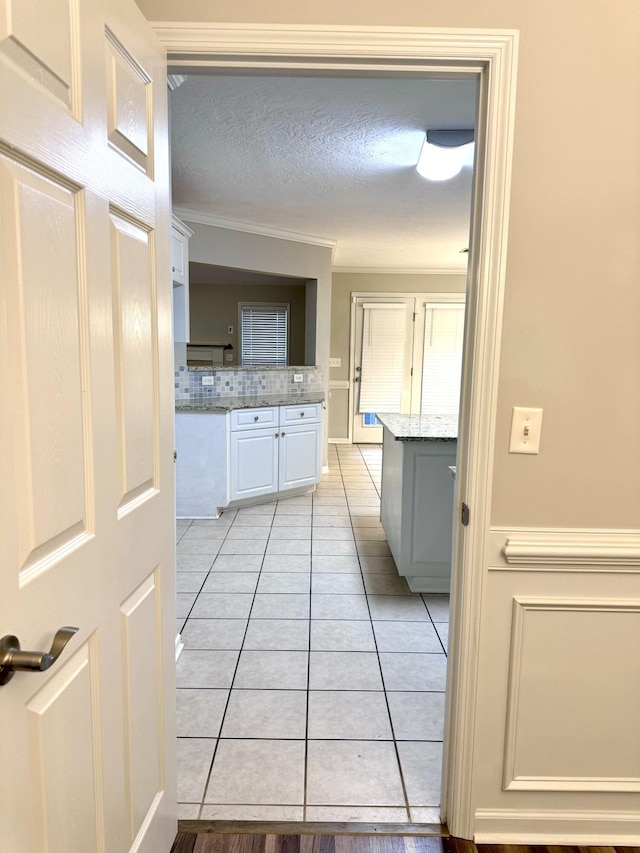 bathroom with tile patterned flooring, decorative backsplash, a textured ceiling, and crown molding