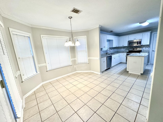 kitchen featuring appliances with stainless steel finishes, crown molding, decorative light fixtures, white cabinets, and a center island