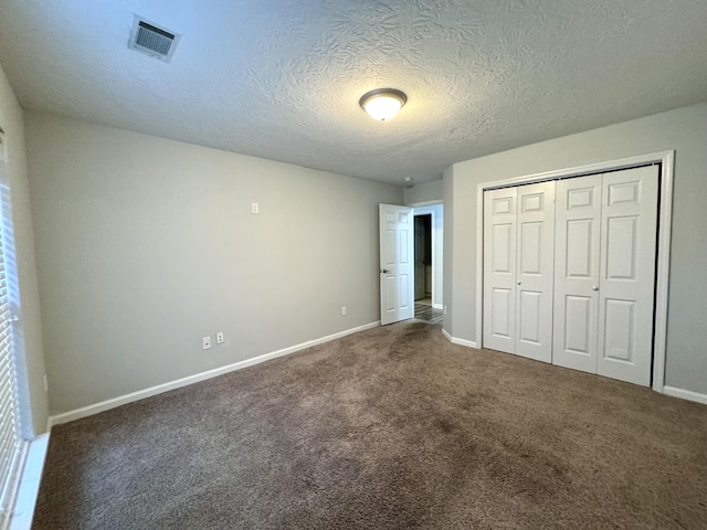 unfurnished bedroom with a closet, dark carpet, and a textured ceiling