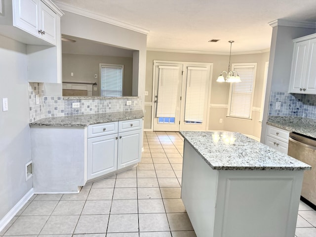 kitchen with hanging light fixtures, tasteful backsplash, light tile patterned flooring, light stone counters, and white cabinetry