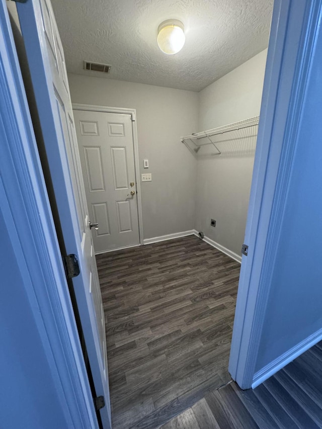 laundry room featuring hookup for an electric dryer, dark wood-type flooring, and a textured ceiling