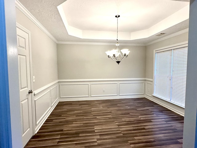 unfurnished dining area with a raised ceiling, a chandelier, a textured ceiling, and ornamental molding