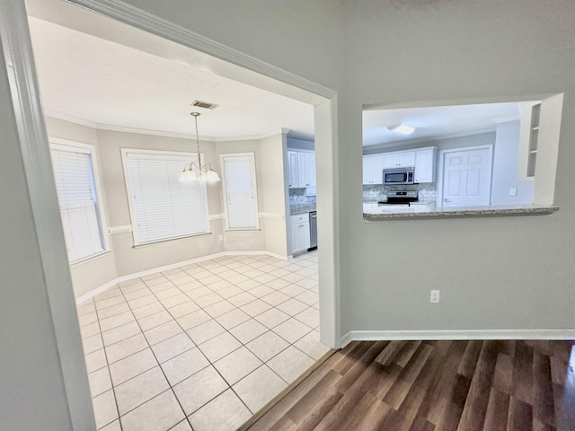 kitchen featuring white cabinetry, ornamental molding, appliances with stainless steel finishes, and tasteful backsplash