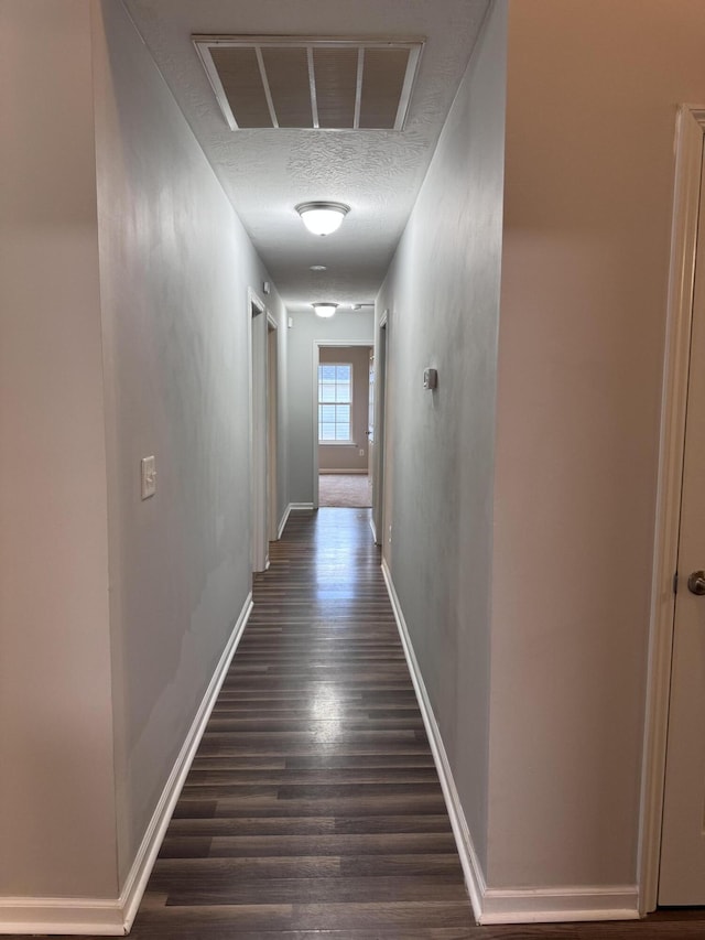 hallway with dark wood-type flooring and a textured ceiling