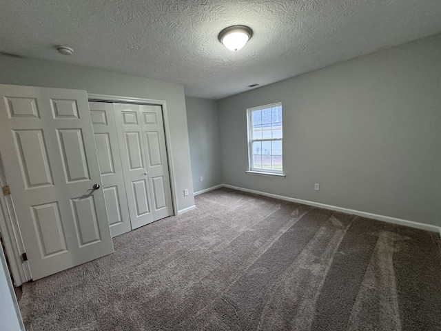 unfurnished bedroom featuring carpet floors, a textured ceiling, and a closet