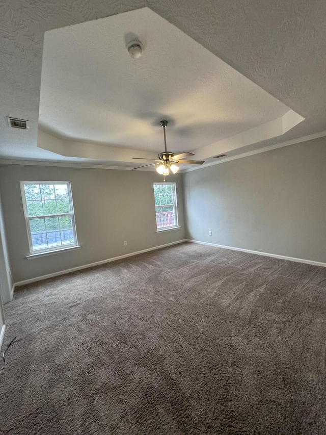 carpeted empty room with ceiling fan, crown molding, a textured ceiling, and a tray ceiling