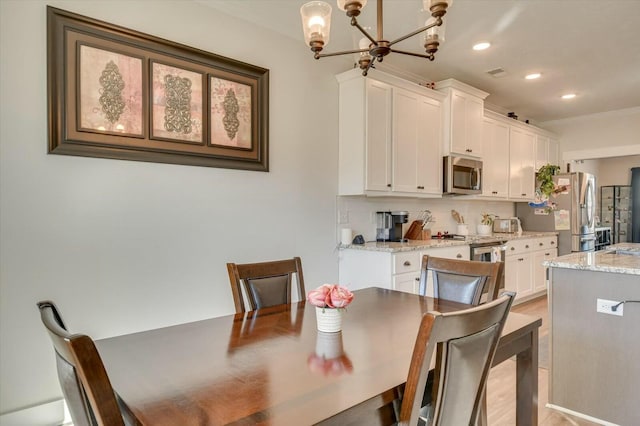 dining space with crown molding, an inviting chandelier, and light hardwood / wood-style floors