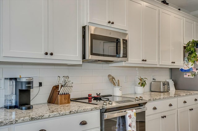 kitchen featuring white cabinetry, tasteful backsplash, light stone countertops, and appliances with stainless steel finishes