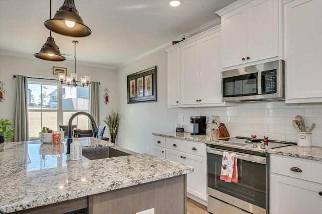 kitchen featuring hanging light fixtures, ornamental molding, stainless steel appliances, and white cabinets