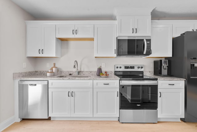 2247 Archer Ln, Augusta, GA 30906 - kitchen with stainless steel appliances, white cabinetry, light wood-style flooring, and light stone countertops