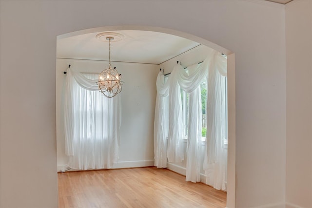 2336 Redwood Dr, Augusta, GA 30904 - empty room featuring arched walkways, baseboards, light wood-type flooring, and a chandelier