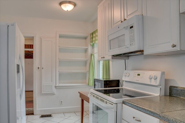 2336 Redwood Dr, Augusta, GA 30904 - kitchen with white appliances, baseboards, dark countertops, white cabinets, and light tile patterned floors