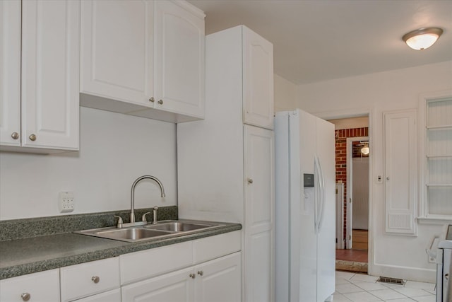 2336 Redwood Dr, Augusta, GA 30904 - kitchen with white appliances, a sink, dark countertops, light tile patterned flooring, and white cabinetry