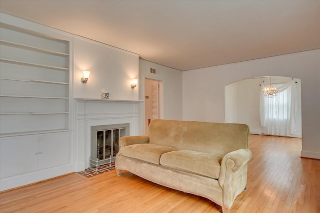 2336 Redwood Dr, Augusta, GA 30904 - living area featuring light wood finished floors, built in shelves, a chandelier, and a fireplace with flush hearth
