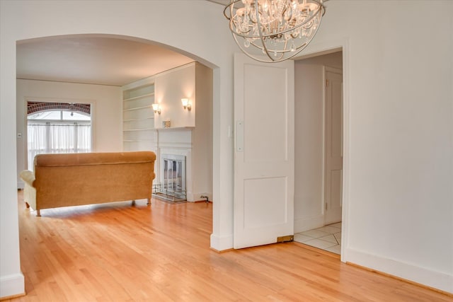2336 Redwood Dr, Augusta, GA 30904 - unfurnished room featuring wood finished floors, a chandelier, arched walkways, built in features, and a glass covered fireplace