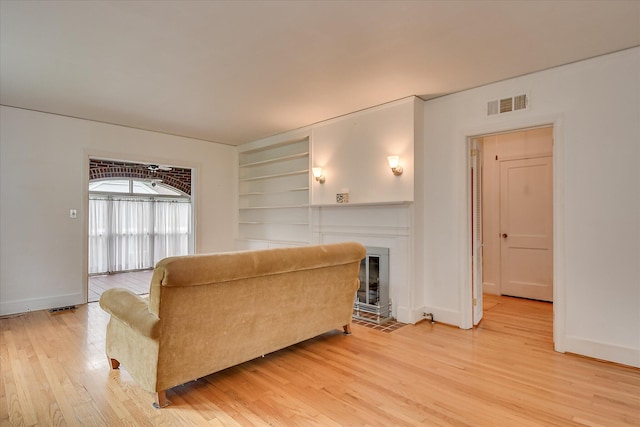 2336 Redwood Dr, Augusta, GA 30904 - living area featuring light wood finished floors, built in features, a fireplace with flush hearth, and baseboards