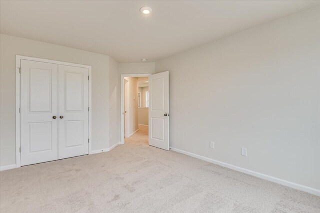 unfurnished bedroom with a closet and light colored carpet