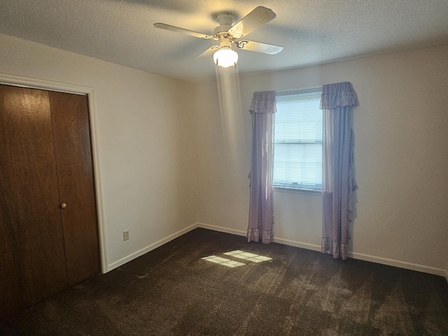 unfurnished bedroom featuring ceiling fan, a closet, a textured ceiling, and dark colored carpet