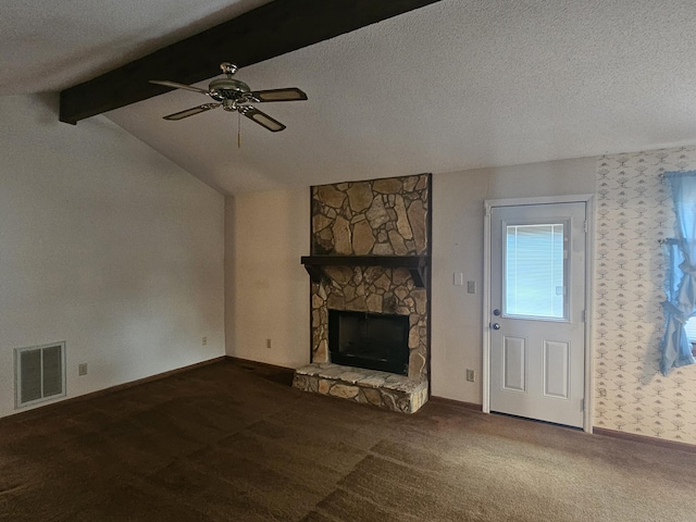 unfurnished living room featuring dark carpet, lofted ceiling with beams, a stone fireplace, ceiling fan, and a textured ceiling