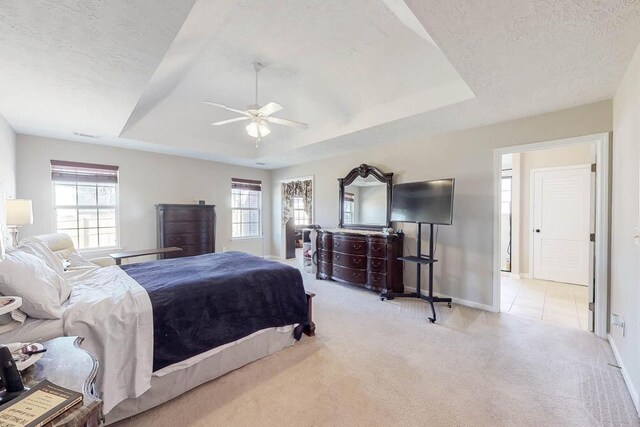 carpeted bedroom featuring baseboards, a raised ceiling, a textured ceiling, and a ceiling fan