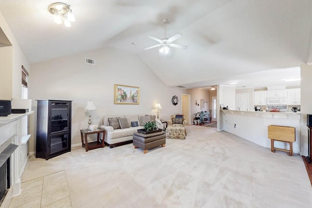 living area featuring high vaulted ceiling, light colored carpet, visible vents, and a tile fireplace