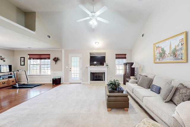 living area with visible vents, carpet, high vaulted ceiling, and a tile fireplace