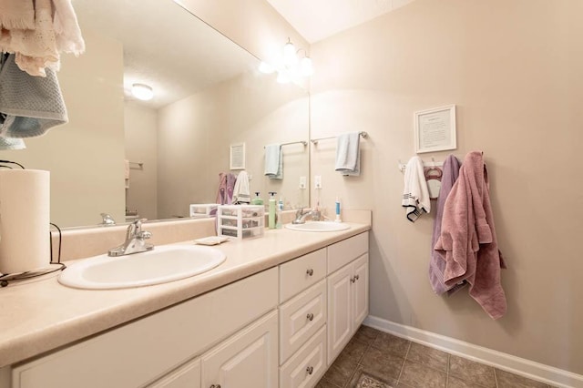 full bathroom with a sink, baseboards, double vanity, and tile patterned flooring