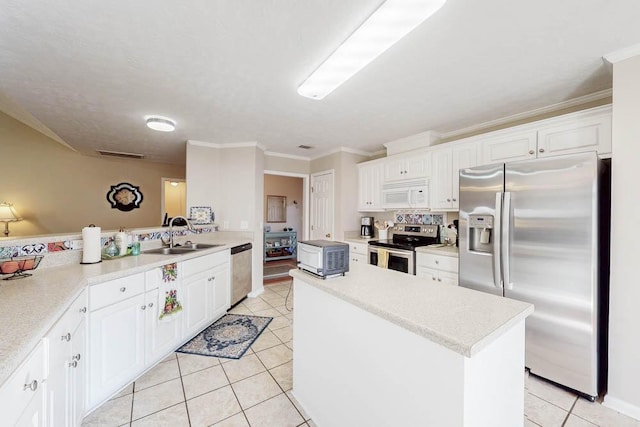 kitchen featuring a center island, appliances with stainless steel finishes, light tile patterned flooring, white cabinetry, and a sink