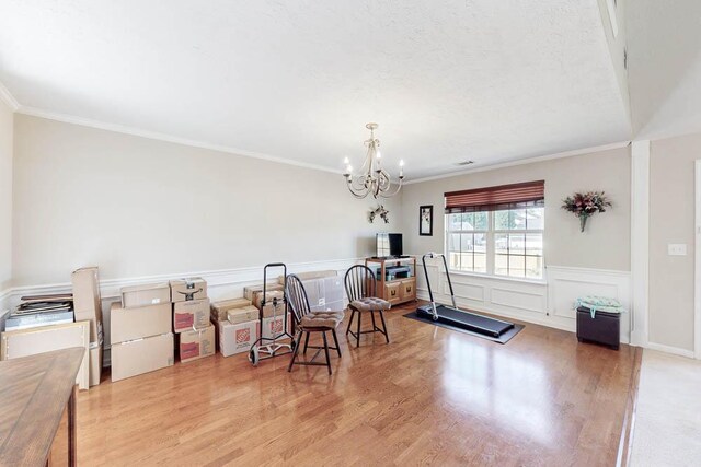 dining room featuring a notable chandelier, a wainscoted wall, crown molding, and wood finished floors