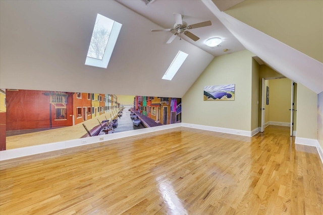 playroom with ceiling fan, lofted ceiling with skylight, and light hardwood / wood-style floors